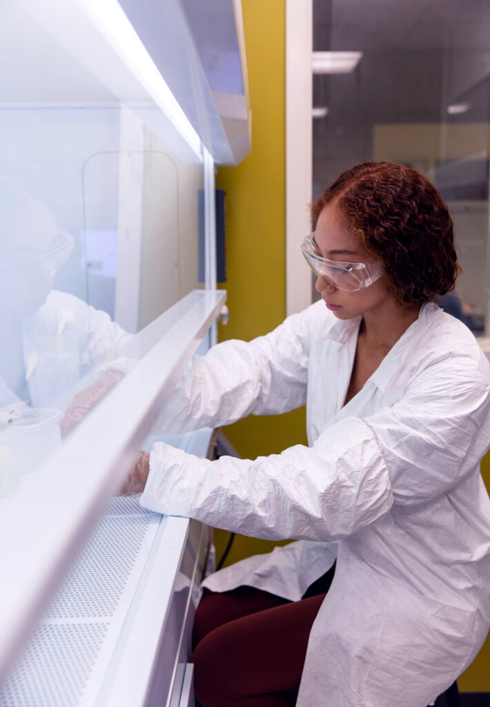 Woman in a lab working on a project with protective gear on.
