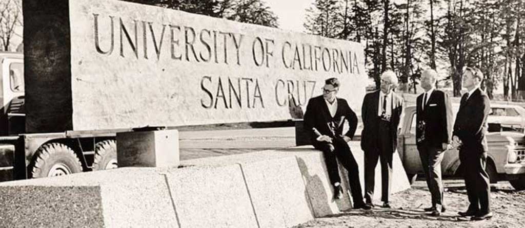 Old photo of board members stood next to UCSC sign.